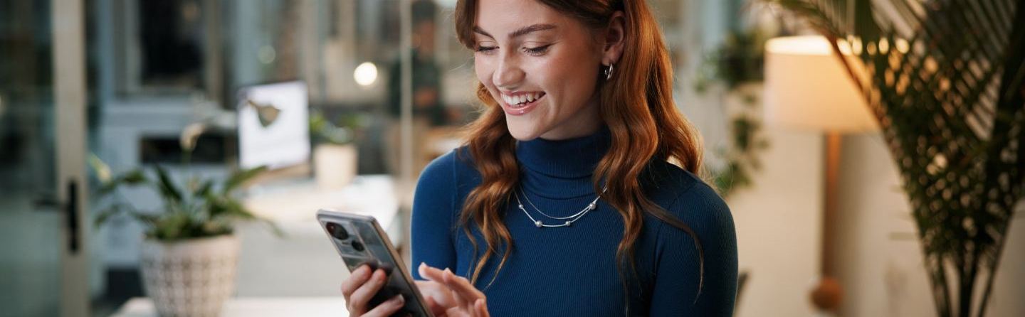 Femme souriante contactant DIAGOME sur smartphone dans un bureau moderne