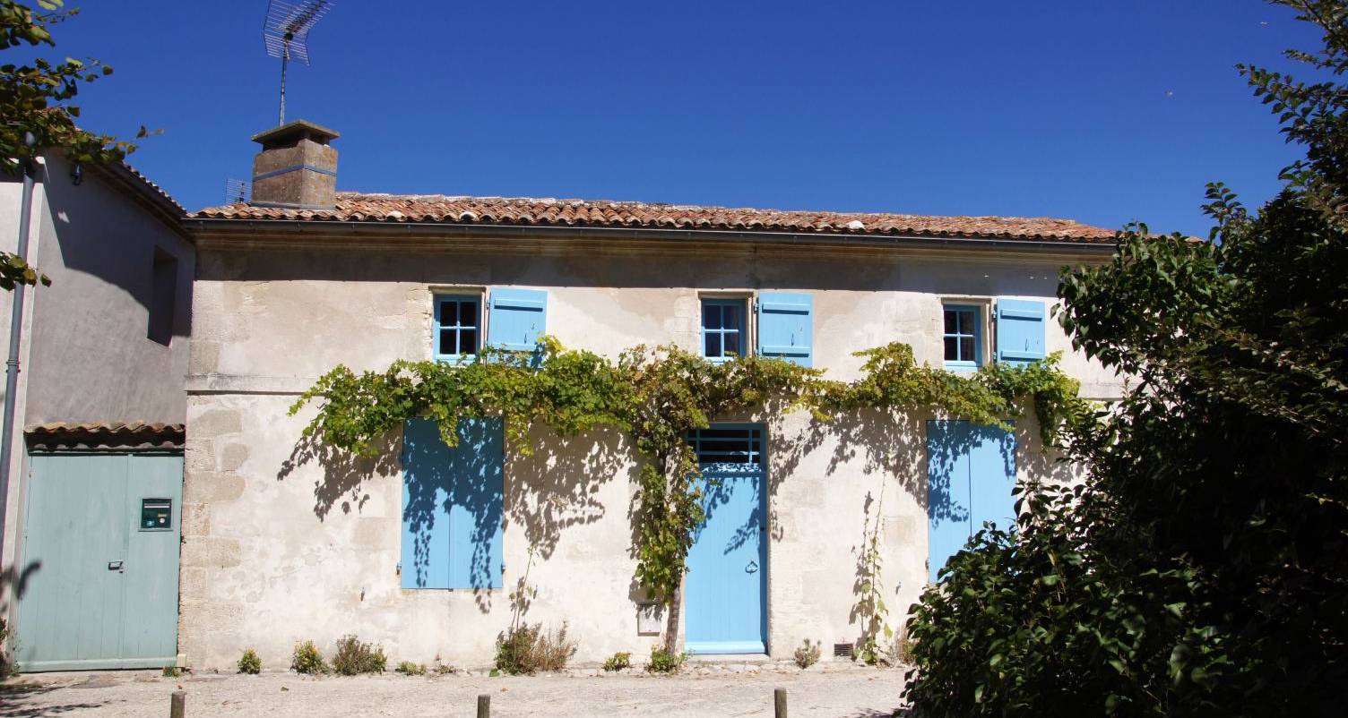 Maison en pierre aux volets bleus et vigne grimpante, bien immobilier en Gironde