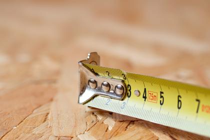 Mètre ruban sur plancher bois pour mesurer une surface, loi Boutin